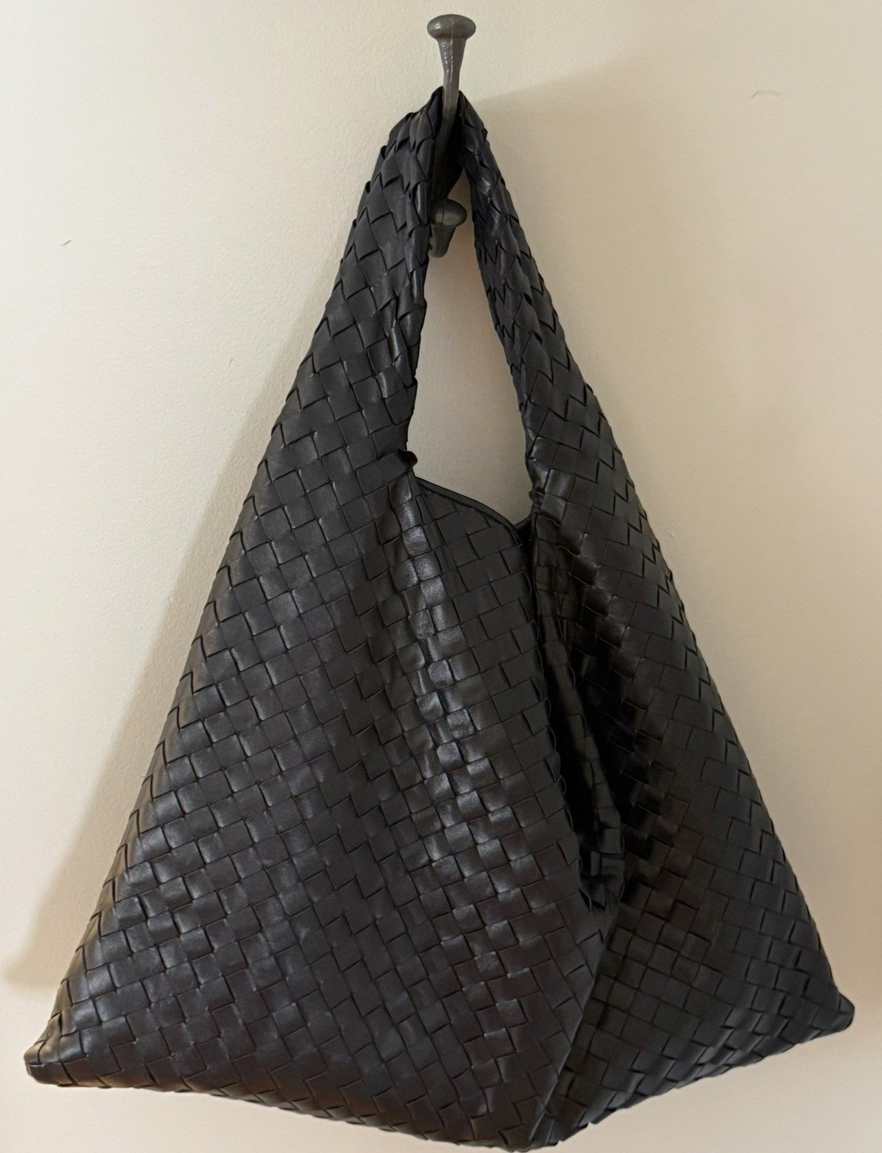 Large woven Bottega Veneta hobo bag hanging on a wall hook