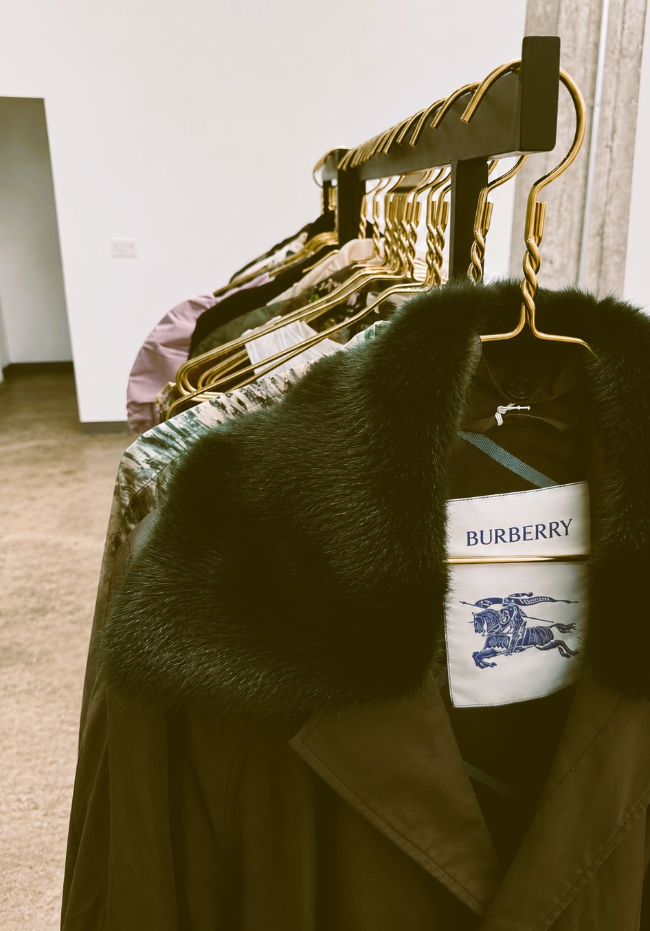 Burberry chocolate trench coat with fur collar hanging on a clothing rack
