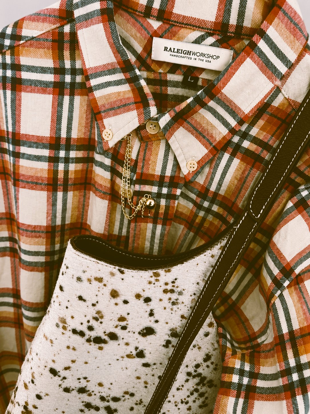 Raleigh Workshop plaid flannel shirt with a cow-print crossbody bag