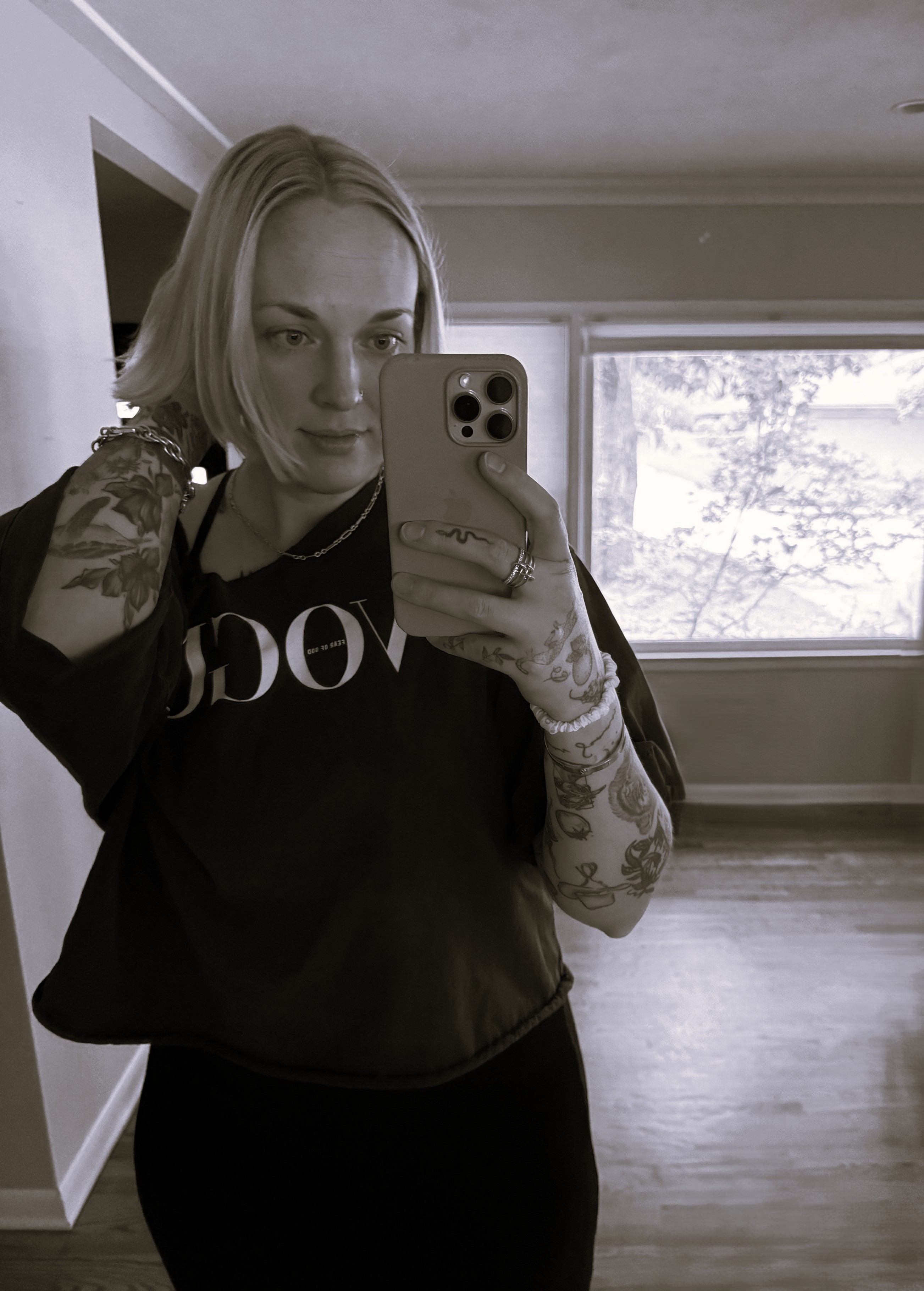 Mirror selfie in black graphic tee, phone in hand